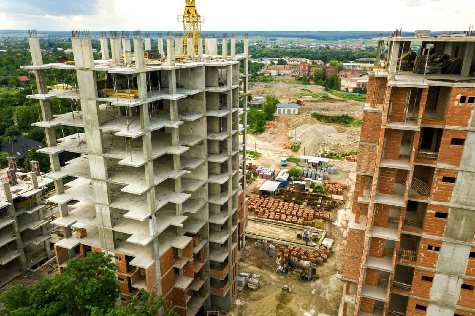 Aerial view of tower lifting crane and concrete frame of tall apartment