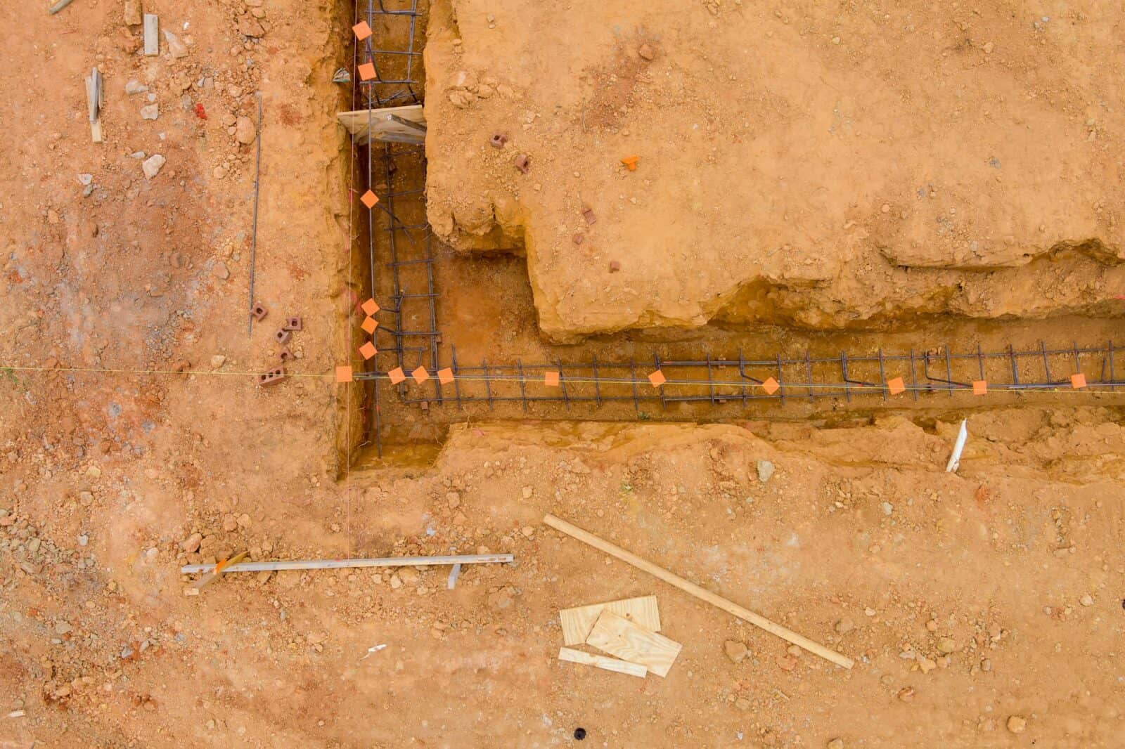 Performing works of putting steel in a trench for a house foundation on a construction site