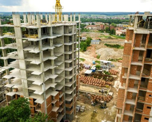 Aerial view of tower lifting crane and concrete frame of tall apartment