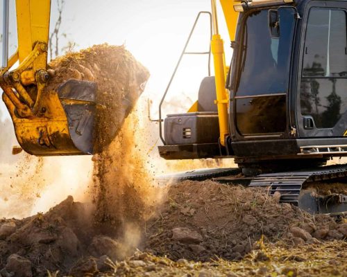 Close-up of excavator at construction site. Backhoe digging soil for earthwork and construction