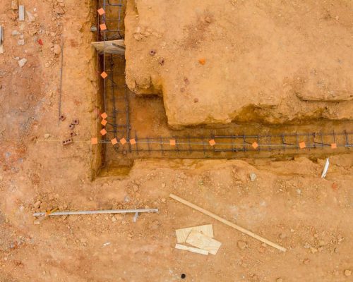 Performing works of putting steel in a trench for a house foundation on a construction site